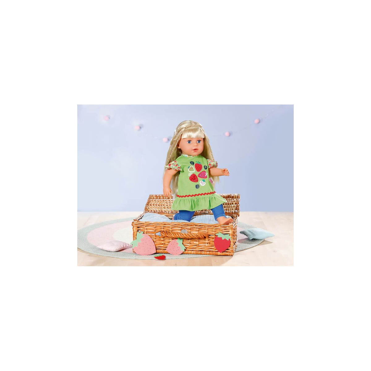 Eine blonde Puppe im grünen Kleid sitzt auf einem mit Erdbeeren verzierten Korb in einem pastellfarbenen Raum. Eine blonde Puppe im grünen Kleid sitzt auf einem mit Erdbeeren verzierten Korb in einem pastellfarbenen Raum.