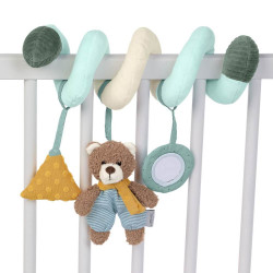 Weiche Spiral-Kinderwagenkette mit Plüschbär, gelbem Dreieck und Spiegel am weißen Gitterbett befestigt.
