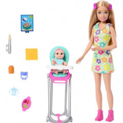 Barbie mit blonden Haaren, Babypuppe im Hochstuhl und diverses Babyzubehör nahe bei arrangiert.
